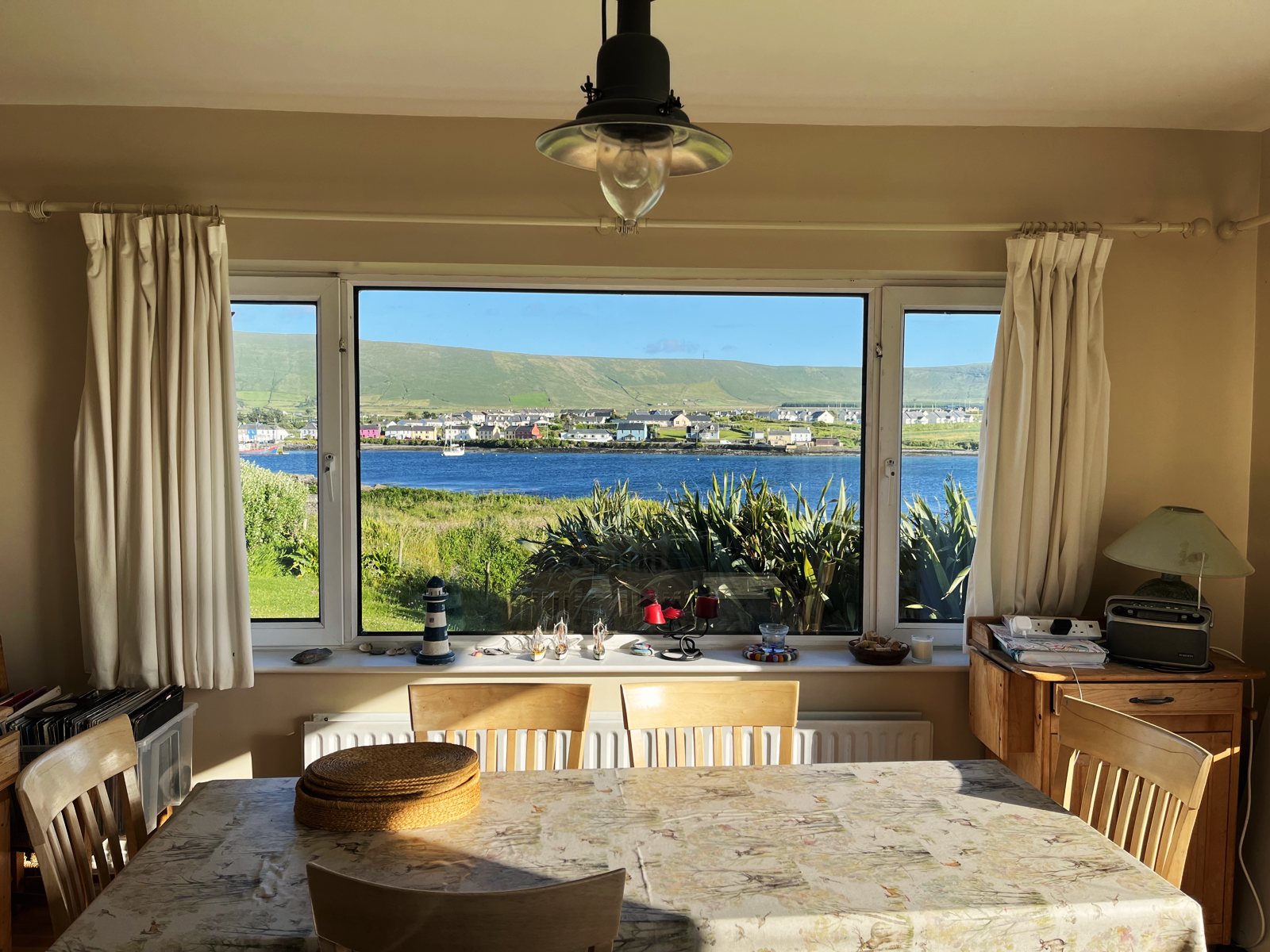 Dining table in front of a wide window looking across the harbour to Portmagee