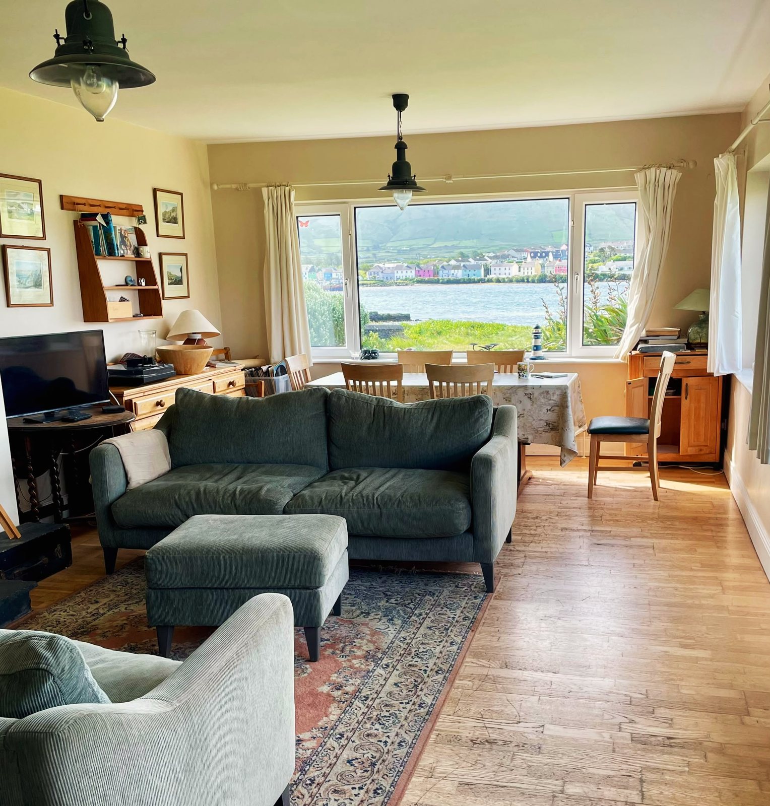 Living room looking past the sofa and dining table to a window over the harbour and Portmagee